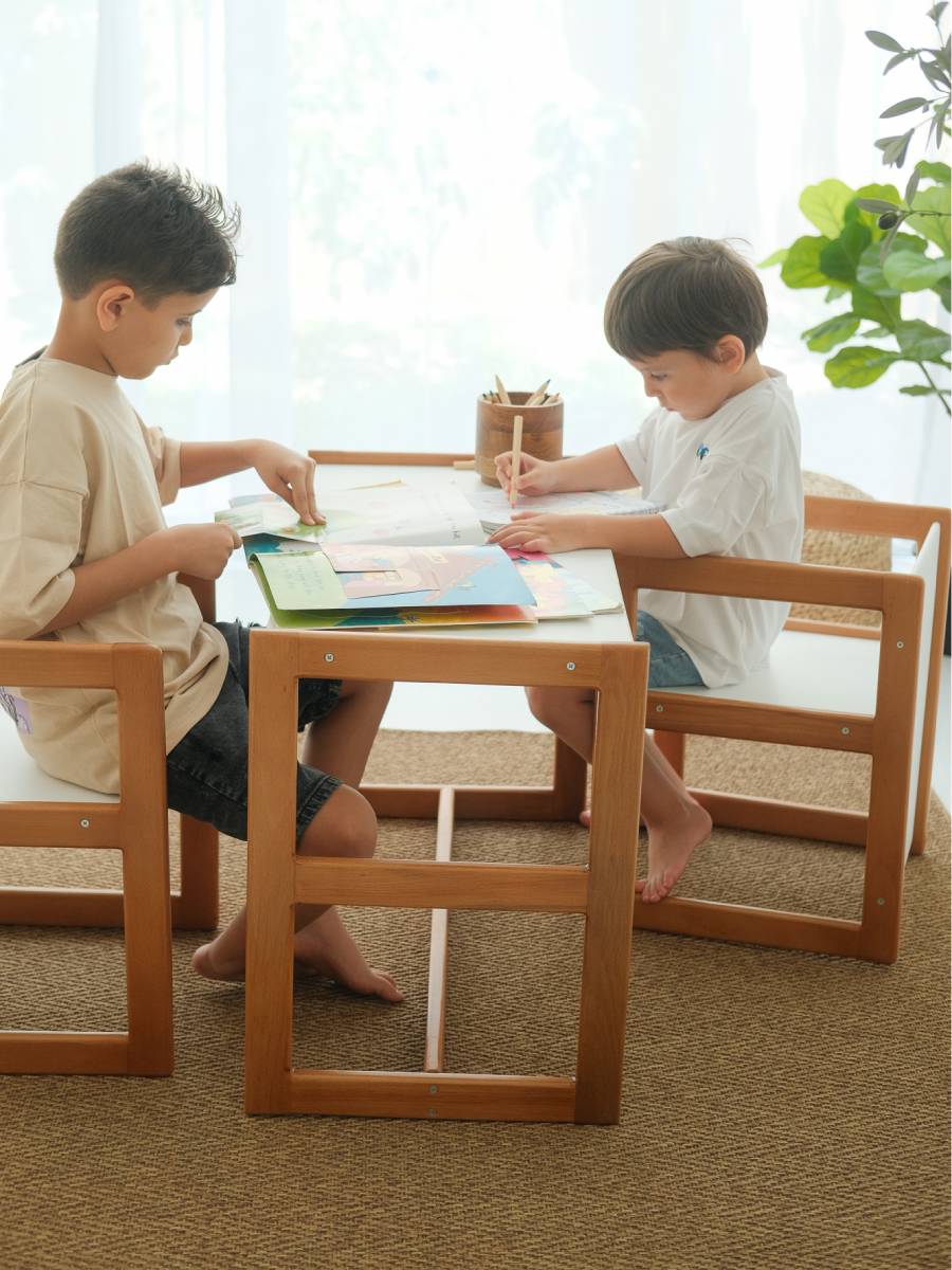 The image shows a creativity bundle consisting of a wooden activity corner duo with a table and two chairs, and a wooden storyhouse bookshelf with various toys and books on the shelves.